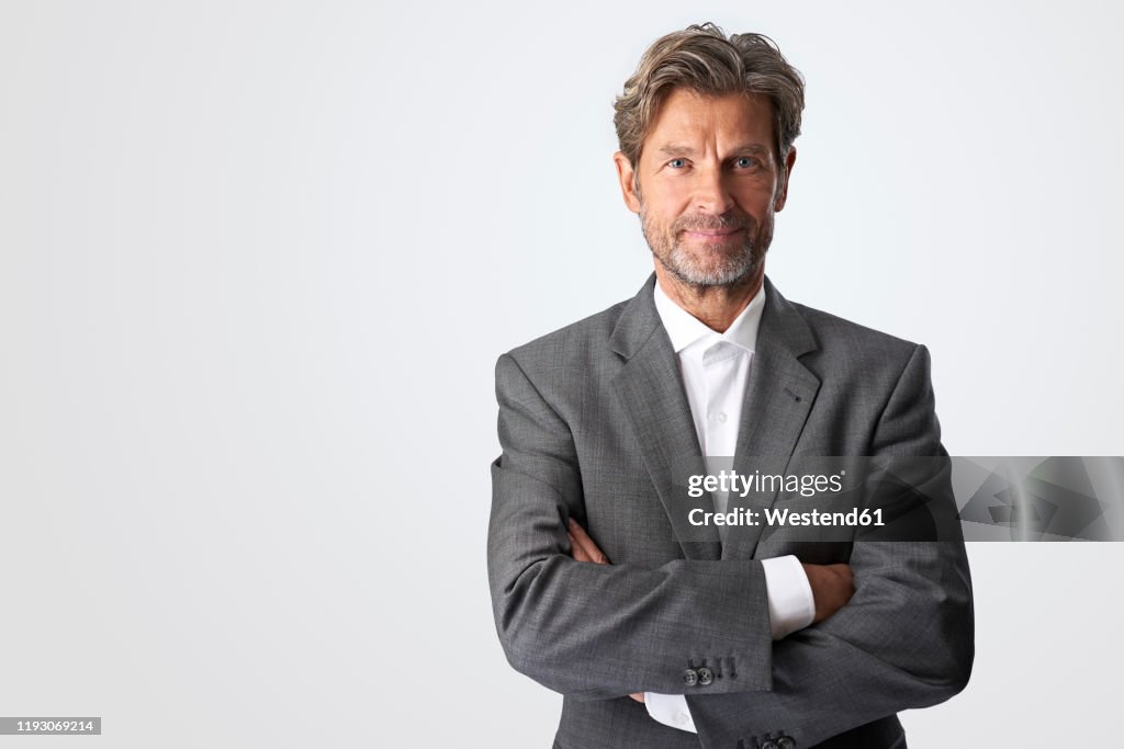 Portrait of smiling mature businessman against light background
