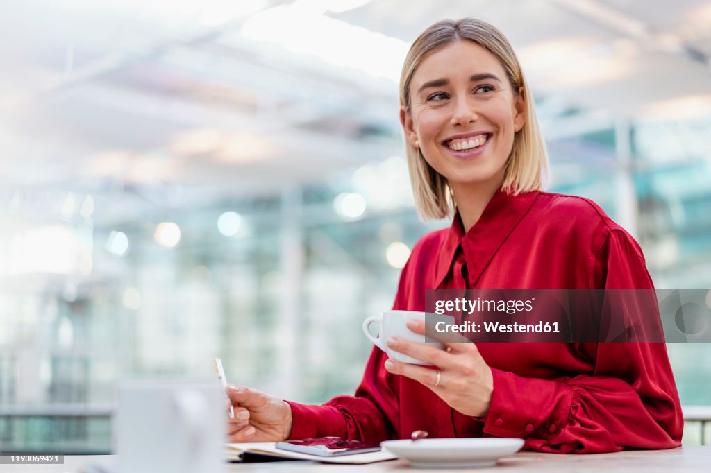 Happy young businesswoman taking notes in a cafe
