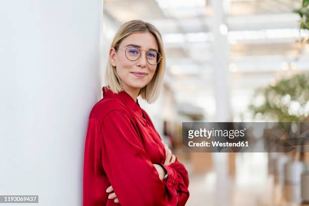 portrait of a confident young businesswoman leaning against a column - young adult stockfoto's en -beelden