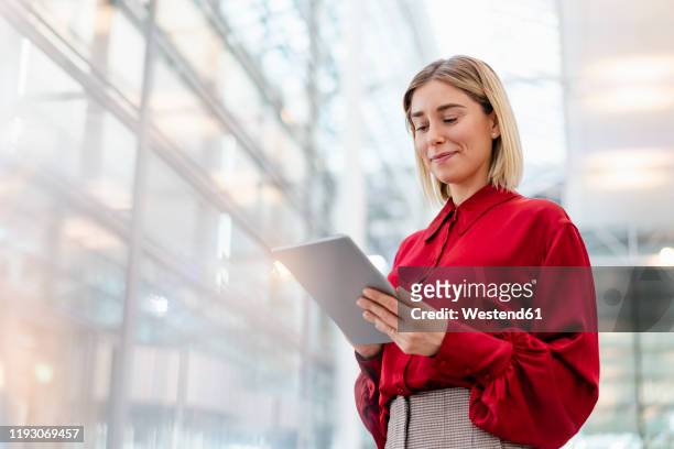 young businesswoman wearing red shirt using tablet - business person ipad travel stock-fotos und bilder