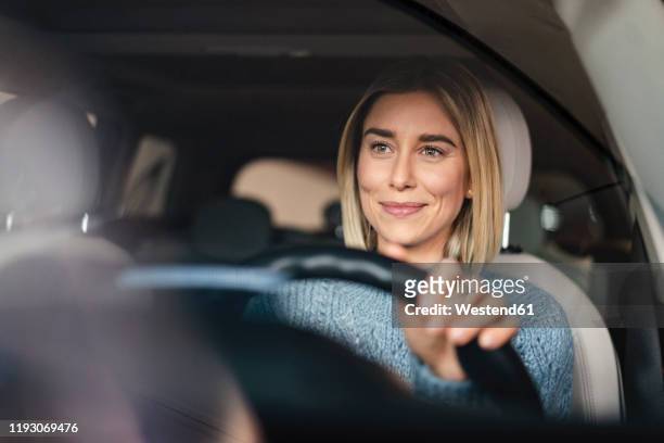 portrait of smiling young woman driving a car - automobile foto e immagini stock