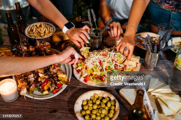 close-up of friends eating during an outdoor dinner - evening meal stock pictures, royalty-free photos & images