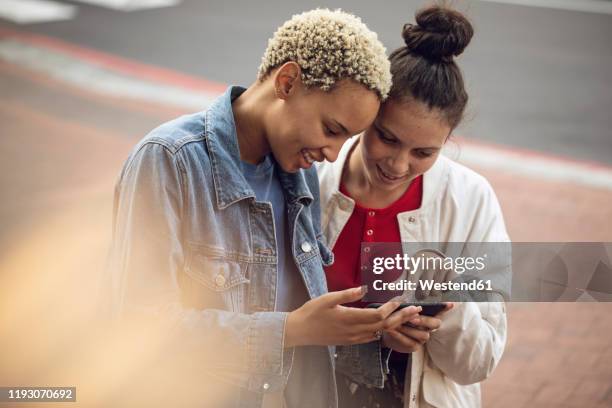 two young women checking smartphone in the city - two people pointing at each other stock pictures, royalty-free photos & images