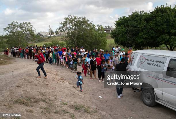 Asylum seekers wait for bottled water at an immigrant camp on December 09, 2019 in Brownsville, Texas, across the river from the border town of...
