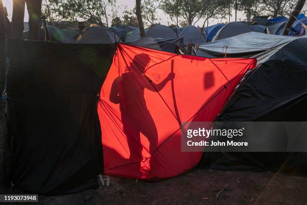 An immigrant from Honduras cleans up her family's living area at a camp for asylum seekers on December 08, 2019 in the border town of Matamoros,...