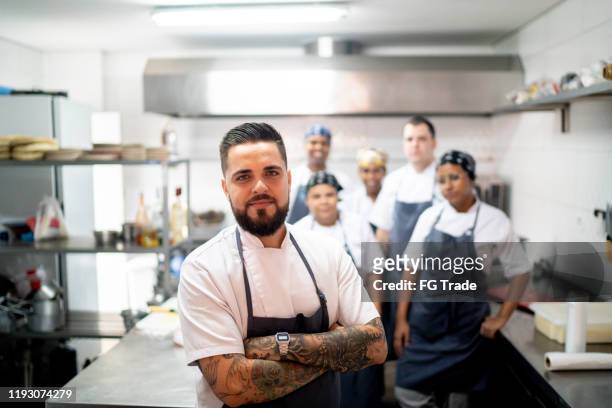 Portrait of restaurant chef with his team in the kitchen