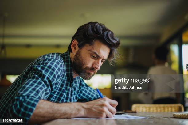 homme mûr remplissant dans la paperasse - écriture photos et images de collection