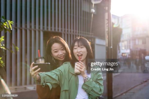 young girls taking selfies with bubble tea in hands - autorretratarse fotografías e imágenes de stock