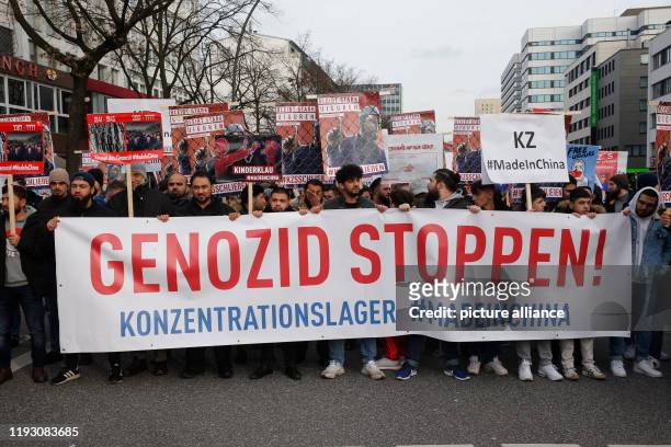 January 2020, Hamburg: Behind a banner with the inscription "Stop Genocide! Concentration camp #MadeinChina" people demonstrate against the...
