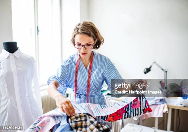 a portrait of young creative woman indoors making old clothes new and trendy. - zoom in stockfoto's en -beelden