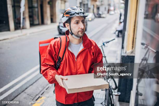 mann liefert pizza in der stadt - pizza delivery stock-fotos und bilder