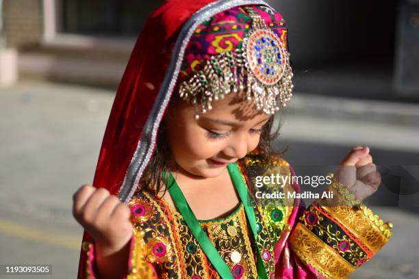 a young girl wearing a traditional pakhtun / afghani dress with traditional / cultural jewelry with happy facial expression - afghan girl stock pictures, royalty-free photos & images