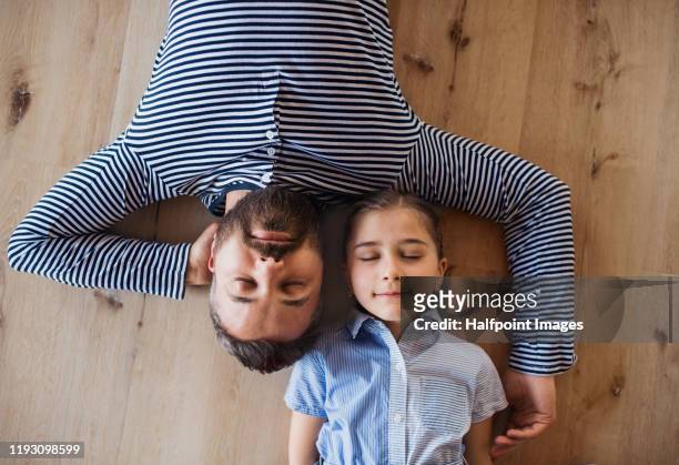 top view of mature father and small daughter lying on floor indoors at home. - platman stockfoto's en -beelden