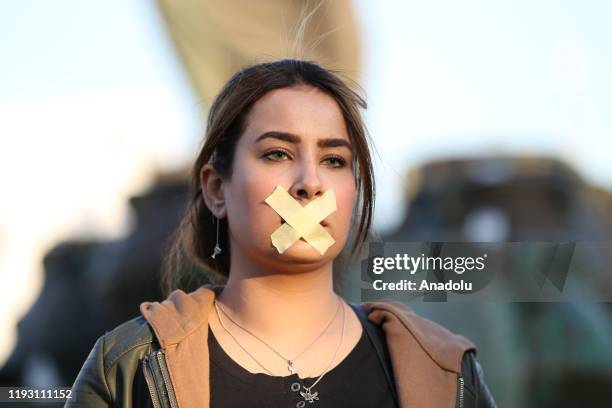 Woman with her mouth crossed-out with a tape takes part in a protest against the attacks towards journalists in Baghdad, Iraq on January 11, 2020. A...