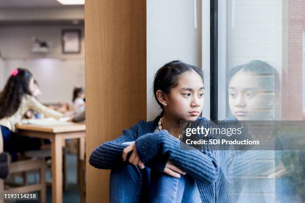 angry middle school girl sits on library windowsill - junior high student stock pictures, royalty-free photos & images