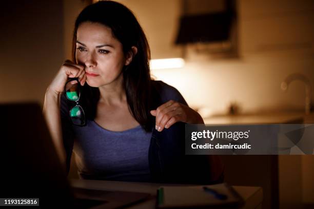 woman working on laptop late at home - concerned laptop stock pictures, royalty-free photos & images