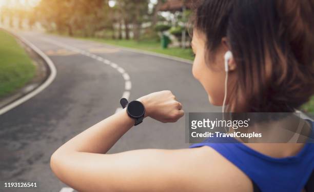 women setting up the fitness smart watch for running. young fitness women runner checking time from smart watch. young woman checking heart rate while jogging in the park. - running gear stock pictures, royalty-free photos & images
