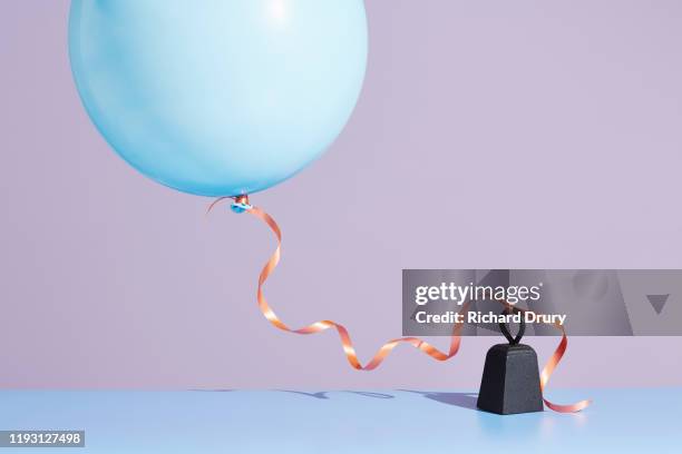 a balloon tied to a metal weight - balloons concept imagens e fotografias de stock