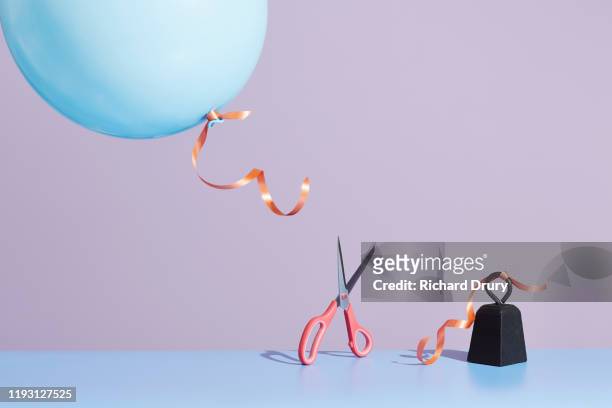a pair of scissors cutting a balloon string to release the balloon - alles hinter sich lassen stock-fotos und bilder