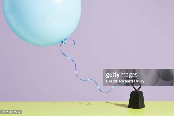 a balloon tied to a metal weight - restraining photos et images de collection