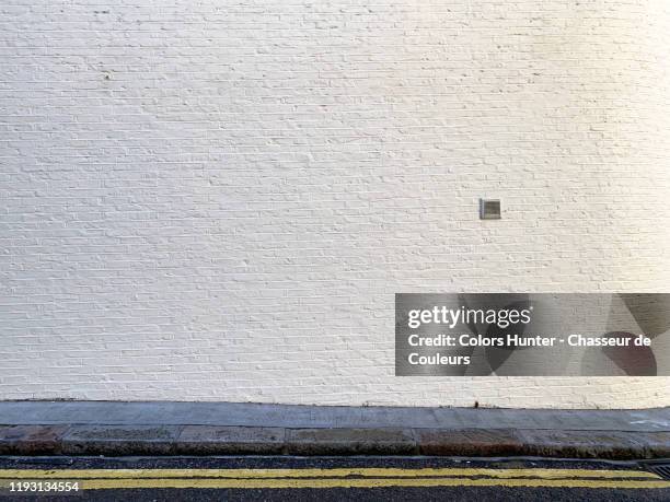 painted bricks wall with sidewalk and street in london - muurschildering stockfoto's en -beelden