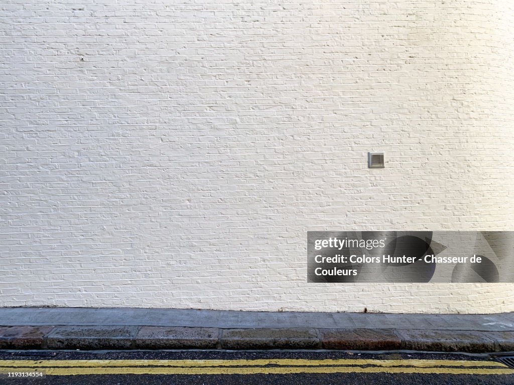 Painted bricks wall with sidewalk and street in London