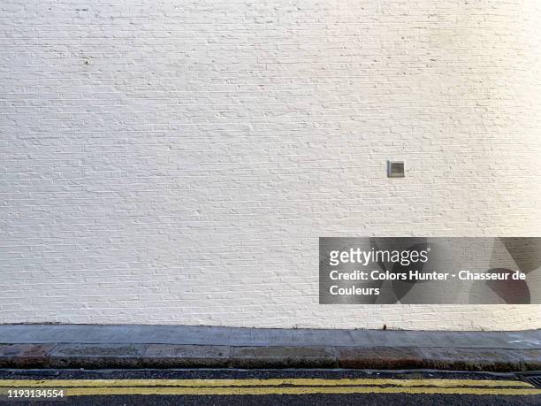 painted bricks wall with sidewalk and street in london - brick wall stock pictures, royalty-free photos & images