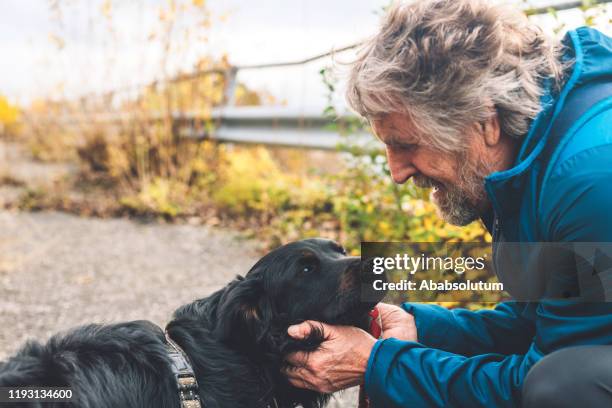 senior man and black dog hiking in southern alps in italy - older people walking a dog stock pictures, royalty-free photos & images