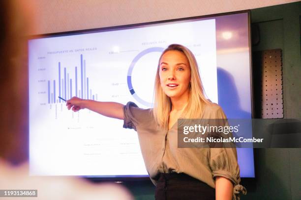 jonge blonde vrouwelijke manager met uitleg over kwartaalresultaten op groot led-scherm - resultaat stockfoto's en -beelden