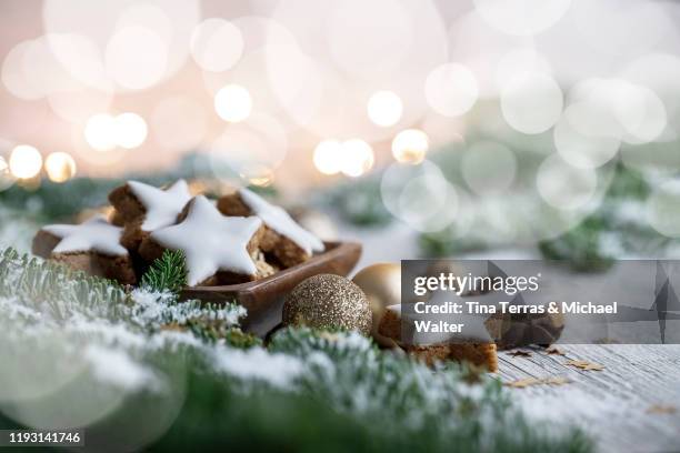 christmas biscuits (zimtsterne) on white wood background with fir green and fairy lights. christmas mood. - tree white background stock pictures, royalty-free photos & images