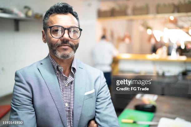 retrato del dueño de un negocio de pie con los brazos cruzados en un restaurante - business owner suit fotografías e imágenes de stock