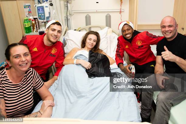 Diogo Dalot and Fred of Manchester United poses with Chloe during the club's annual Christmas hospital visits at Royal Manchester Children's Hospital...