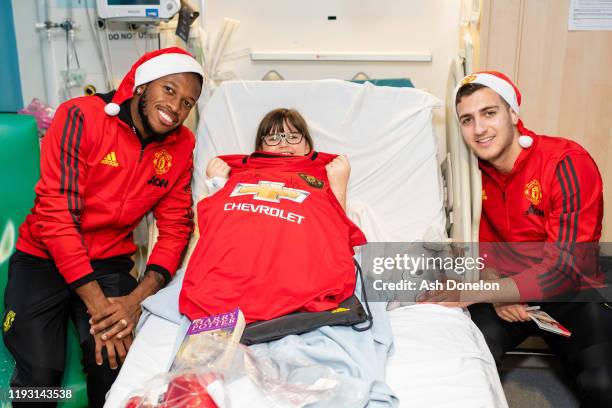 Diogo Dalot and Fred of Manchester United poses with Olivia during the club's annual Christmas hospital visits at Royal Manchester Children's...
