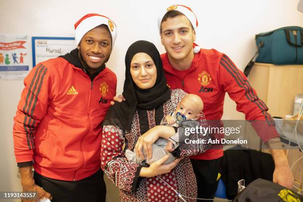 Diogo Dalot and Fred of Manchester United poses with Mursal, 3 months, during the club's annual Christmas hospital visits at Royal Manchester...