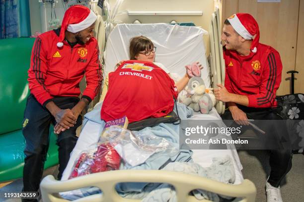 Diogo Dalot and Fred of Manchester United poses with Olivia during the club's annual Christmas hospital visits at Royal Manchester Children's...