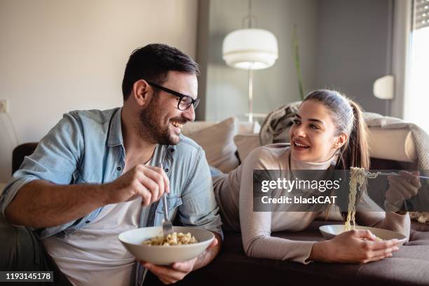 giovane coppia che mangia noodles a casa - soup home foto e immagini stock