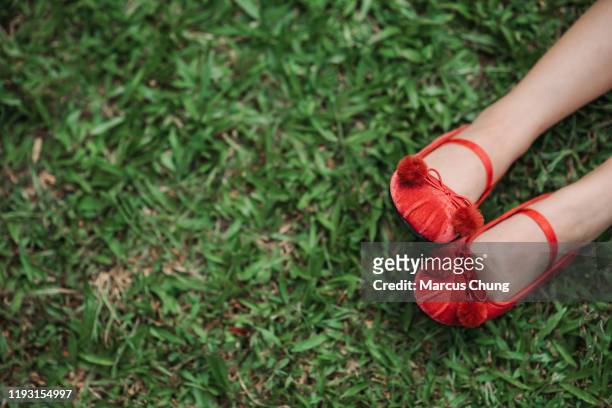 two legs with pretty red shoes showing on the grasses - girls shoes stock pictures, royalty-free photos & images
