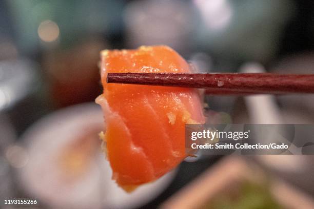 Close-up of chopsticks holding ora king salmon during grand opening event at Bamboo Sushi, an environmentally sustainable restaurant in City Center...