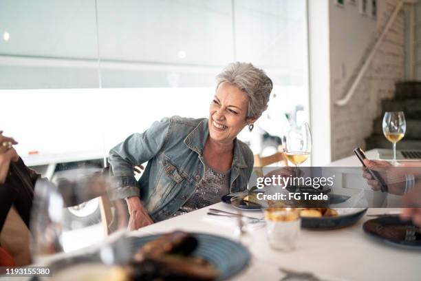 senior friends having lunch in a restaurant, talking and laughing - senior women wine stock pictures, royalty-free photos & images