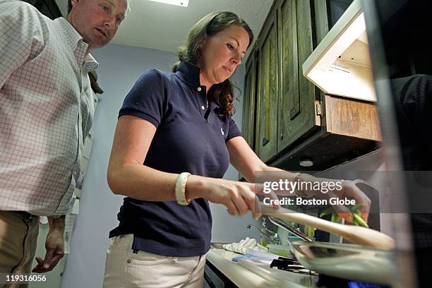 Newlyweds Holt and Kate Wood are pictured in theIr kitchen as Holt watches Kate stir food in a teflon pan with a wooden spoon.