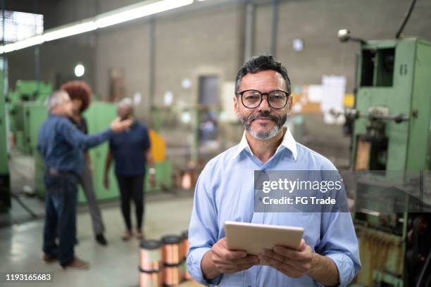 porträt eines geschäftsmannes, der ein digitales tablet in der produktionslinie einer fabrik verwendet - maschinenbau stock-fotos und bilder