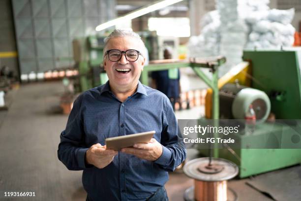 portret van een zakenman met behulp van een digitale tablet in de productielijn van een fabriek - industrial portrait stockfoto's en -beelden