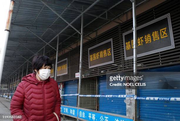 Woman walks in front of the closed Huanan wholesale seafood market, where health authorities say a man who died from a respiratory illness had...