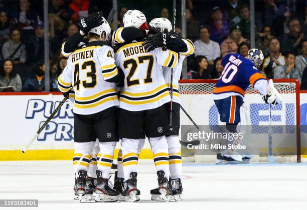 John Moore of the Boston Bruins is congratulated by his teammates after scoring a third period goal past Semyon Varlamov of the New York Islanders at...