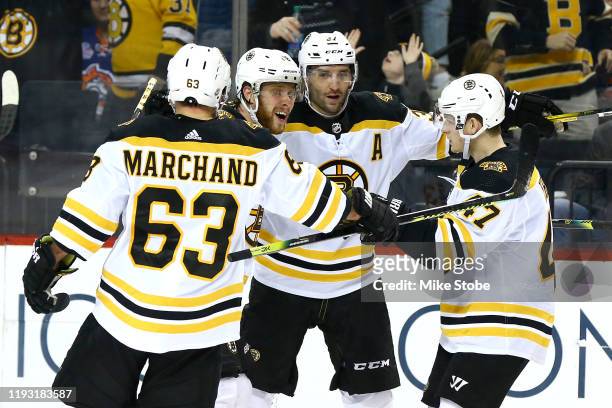 Patrice Bergeron of the Boston Bruins is congratulated by his teammates after scoring the game winning goal in overtime against the New York...