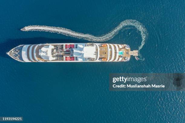 top down aerial image large holiday cruise ship in the middle of the ocean with the small speed boat across around. - cruise liner ストックフォトと画像