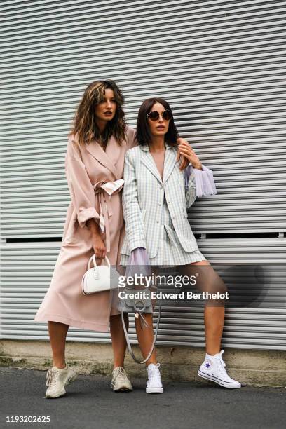Guest wears a pale pink wrap-over oversized trench coat, a white bowling bag, cream-color Gucci sneakers ; A guest wears Dolce & Gabbana sunglasses,...