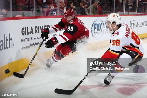 Alex Goligoski of the Arizona Coyotes attempts to play the puck under pressure from Andrew Mangiapane of the Calgary Flames during the second period...