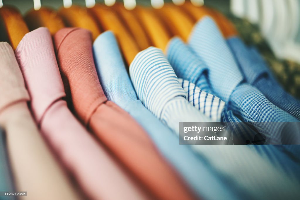 Assortment of mens shirts on wooden coat hangers