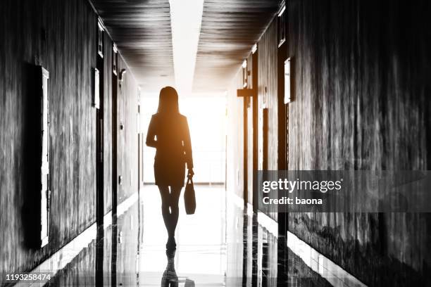 businesswoman through the office corridor - woman walking out door silhouette stock pictures, royalty-free photos & images